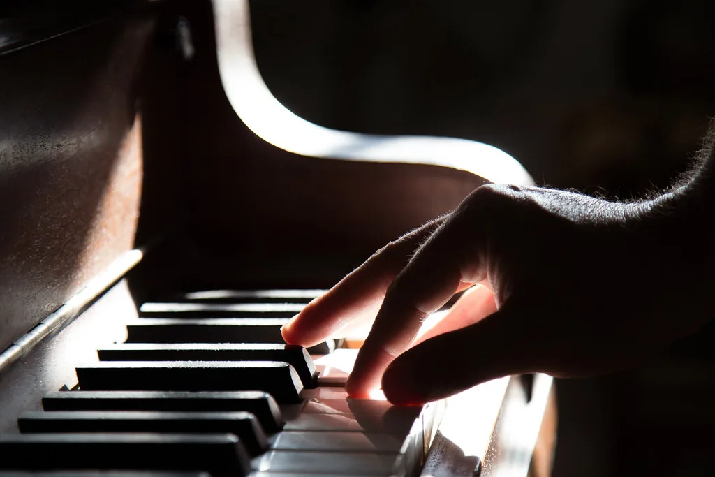 Hand playing a piano keyboard Hand playing a piano keyboard