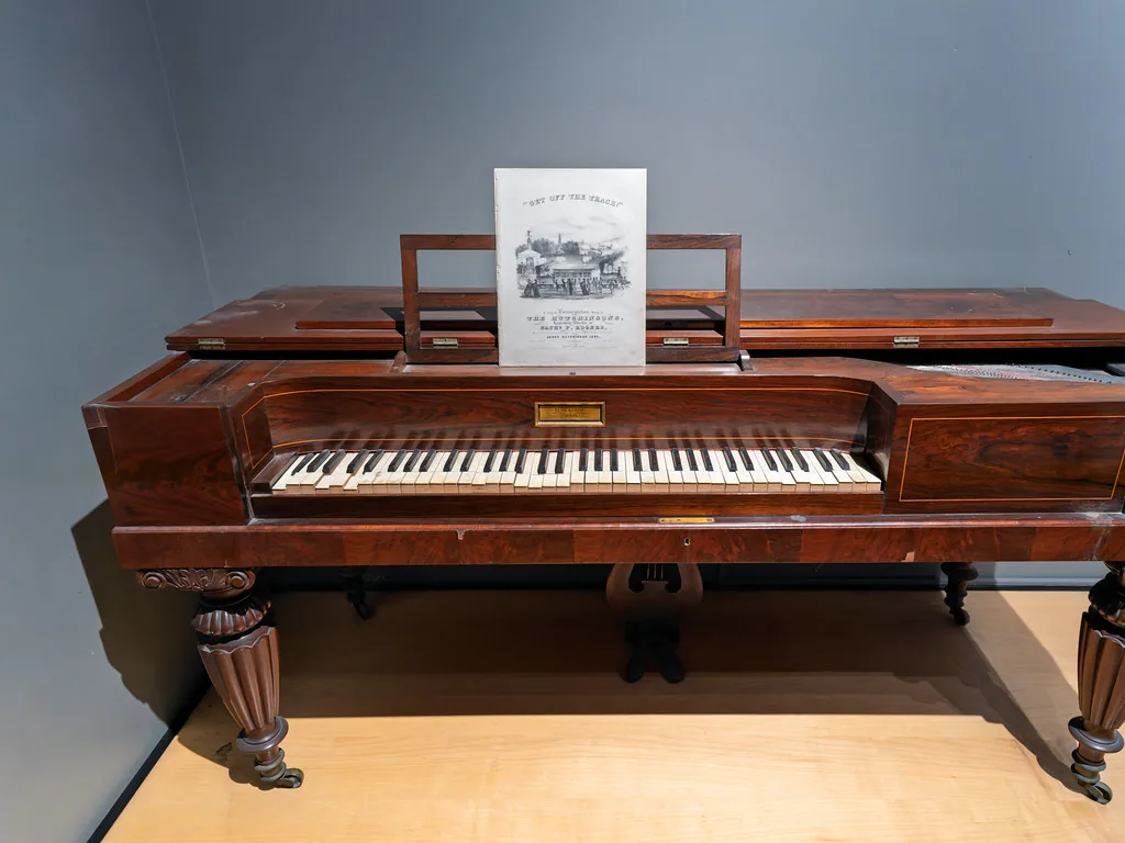 Piano ancien exposé sur son piètement Piano ancien exposé sur son piètement